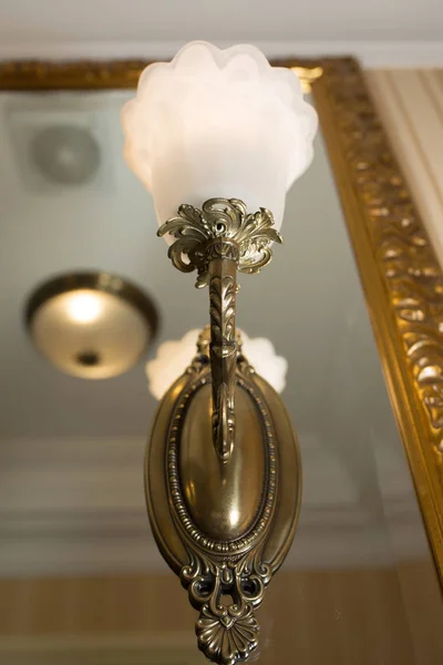 ミラーの近くにぶら下がっている金の金属から作られたレトロなスタイルのウォール ランプ — ストック写真