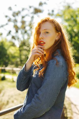 Şık kırmızı saçlı Genç kadın Street güneş ışınlarının poz kot gömlek