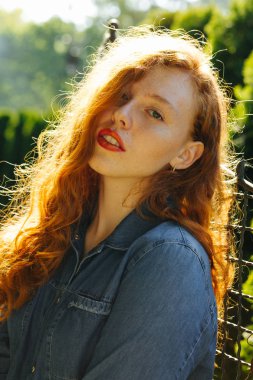 Güzel kırmızı saçlı kız kot gömlek Street güneş ışınlarının poz