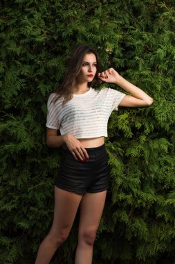 Trendy giyim bir yeşil mazı arka plan üzerinde poz çarpıcı esmer kadın