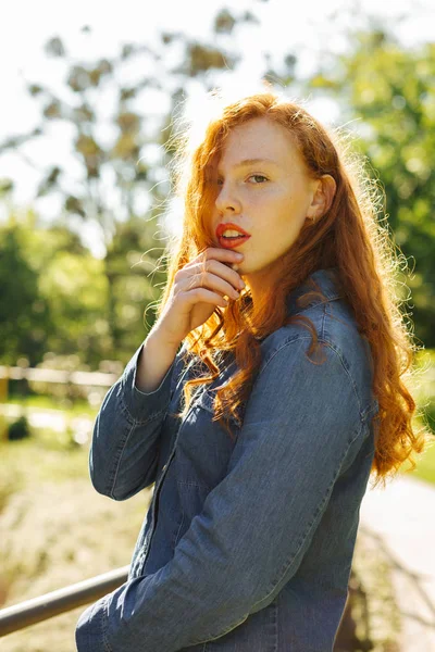 Şık kırmızı saçlı Genç kadın Street güneş ışınlarının poz kot gömlek