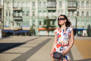 Muhteşem esmer modeli trendy elbise ve gözlük, sokağın poz. Boş alan