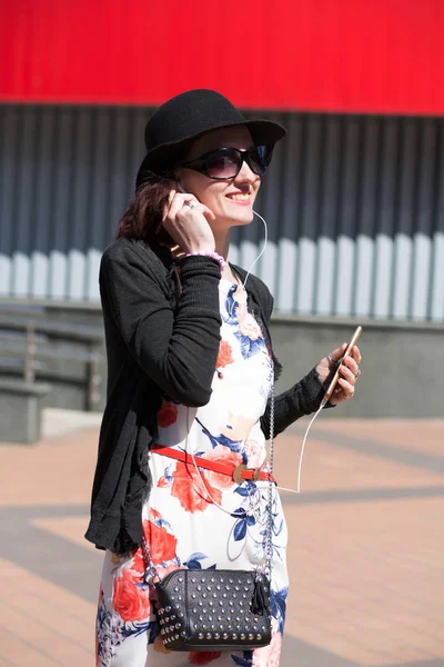 Улыбающаяся Брюнетка Модной Шляпе Солнечных Очках Слушающая Музыку Мобильном Телефоне — стоковое фото