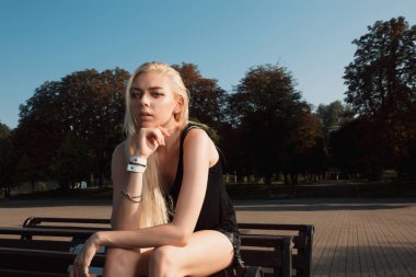 Güneşli bir günde bir bankta poz rahat kıyafetler şık sarışın model