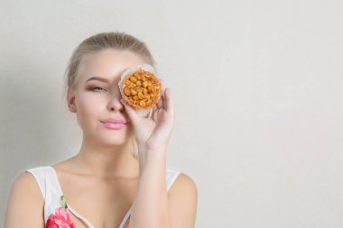 Güzel sarışın genç kadın el ve holding şekerli krema tatlı suratından kapsar. Boş alan