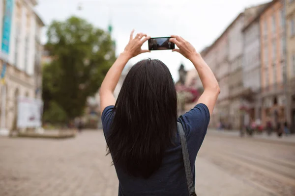 游客步行穿过利沃夫市中心 在她的手机上拍照 — 图库照片