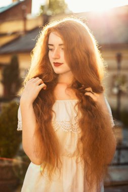Gün batımında güneş parlamayı poz çıplak omuz ile lüks kırmızı saçlı kadın