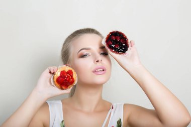 Tatlı kek çilek yüzünü yakınındaki ile tutarak profesyonel makyaj ile çok güzel sarışın kadın