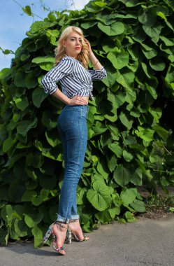 Çizgili bluz ve kot yeşil yaprakları arka plan poz, kıvırcık saçlı şık genç modeli