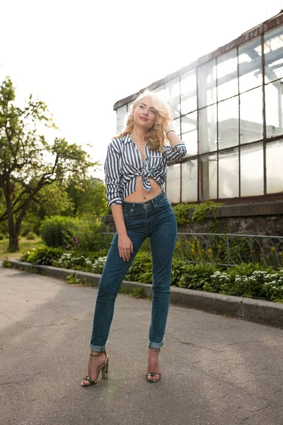 Çizgili gömlek, kot giyen ve yumuşak akşam güneş ışığı ile poz güzel genç modeli