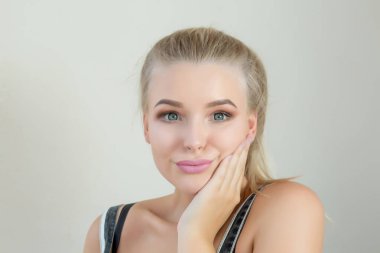 Mükemmel makyaj gri bir arka plan üzerinde poz ile ifade sarışın kız. Boş alan