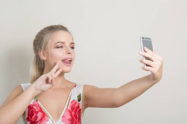 Dilini gösteren ve selfie üstünde hareket eden telefon yapmak duygusal sarışın kadın 