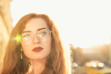 Yumuşak güneş ışığı akşam poz kıvırcık saçlı güzel kırmızı saçlı kız closeup portresi. Metin için yer