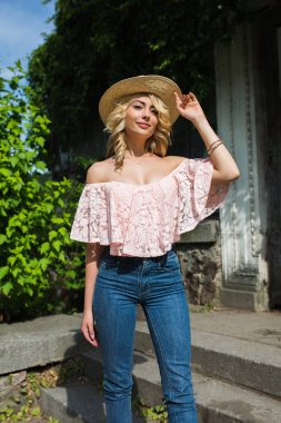 Hasır şapka ve çıplak omuz ile dantel bluz giyen yemyeşil dalgalı saçlı zarif genç modeli
