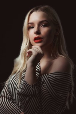 Dramatik karanlıkta poz kırmızı dudaklar çizgili bluz giyen genç sarışın kız portresi