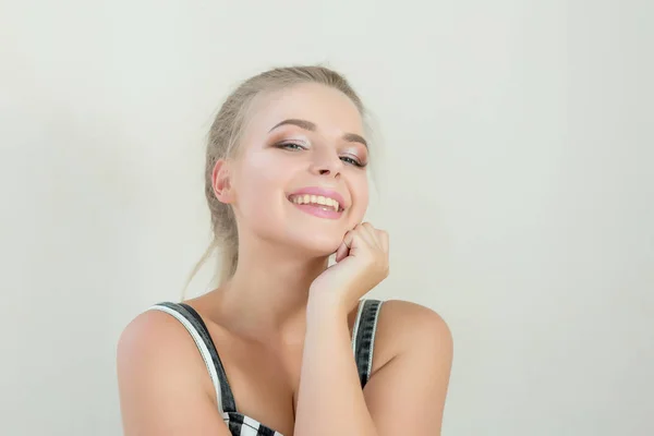 Positive blonde girl with beautiful makeup posing on a white background. Empty space