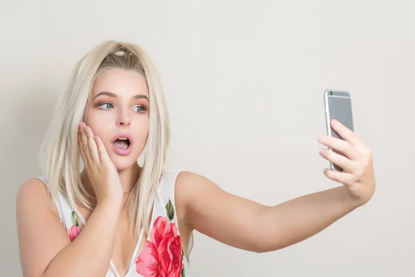 Overrasket Blond Modell Som Lager Selfie Mobiltelefonen Mot Grå Bakgrunn – stockfoto