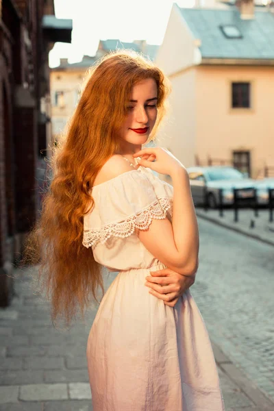 Akşam güneş ışığında poz beyaz elbise uzun kıvırcık saçlı kırmızı saçlı modeli