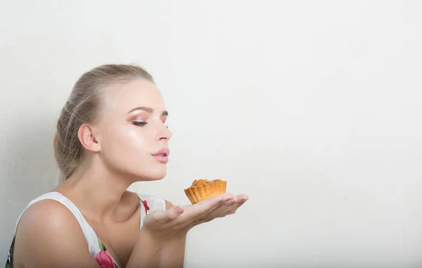 Sexy blonde woman with natural makeup holding savory dessert with nuts. Empty space