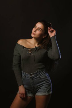 Moda modeli test çekimi şık kız karanlık Studio'da poz gri iç çamaşırı ve kot şort giymiş