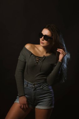 Moda modeli test çekimleri inanılmaz kadın koyu Studio'da poz gri iç çamaşırı ve kot şort giymiş