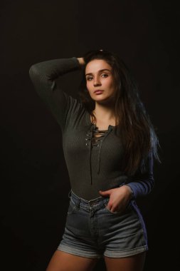 Moda modeli test çekimi güzel kadının karanlık Studio'da poz gri iç çamaşırı ve kot şort giymiş