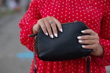 Güzel manikür siyah deri çanta holding ile el. Closeup çekim