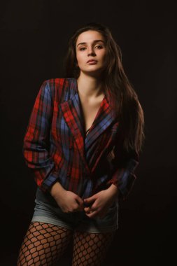 Uzun saçlı kareli ceket gölgeler bir karanlık studio zemin üzerine poz baştan çıkarıcı genç modeli