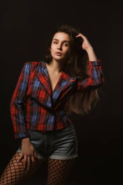 Kareli ceket gölgeler bir karanlık studio zemin üzerine poz uzun saçlı Glamour genç model