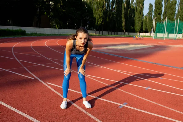 Bir stadyum üzerinde yarışın başlamasından bekleyen kadın sportif modeli. Boşaltmak