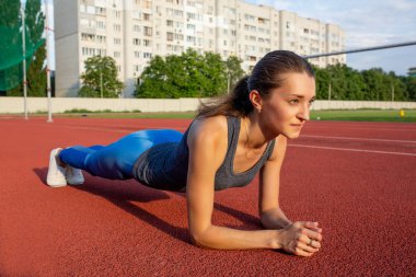 Atletik esmer kadın tahta egzersiz açık stadyum spor giyim