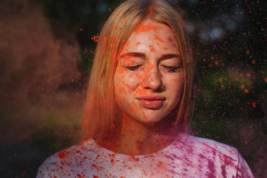 Harika beyaz sarışın model Holi Festivali turuncu kuru boya patlayan ile poz