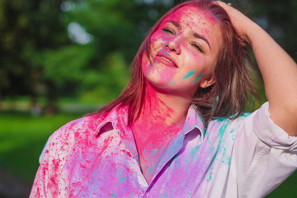 Pleased caucasian brunette girl playing with pink dry paint at the Holi Festival 