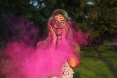 Holi festival kutlayan pembe kuru boya bulutu n ayakta IOmuz kıvırcık saç beyaz kız memnun