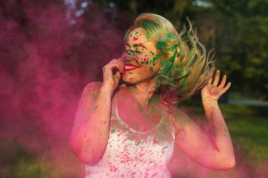 Holi festival kutluyor mutlu kafkas kadın kıvırcık saçlı pembe kuru boya, bulutu n ayakta