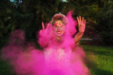 Holi festival kutluyor ifade kafkas kadın kıvırcık saçlı pembe kuru boya, bulutu içinde poz