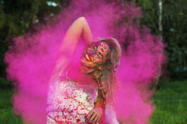 Holi festival kutluyor pembe kuru boya, bulutu içinde poz kıvırcık saçlı beyaz kız gülerek