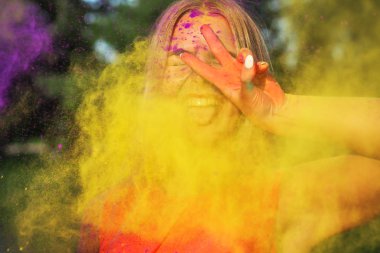 Sarı boya Holi gösteren barış hareketi bulutu içinde duran genç kadın gülüyor