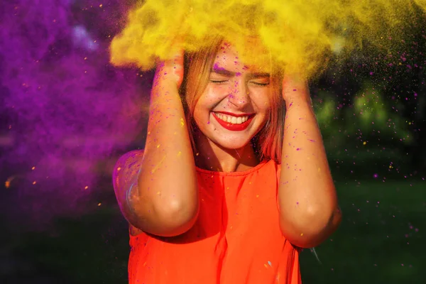快乐的年轻女孩站在黄色和紫色的油漆云在夏季的节日节 — 图库照片