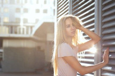 Baştan çıkarıcı sarışın kız uzun saçlı güneş parlama ile panjurlar, poz. Boş alan