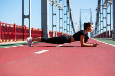 Tahta egzersiz köprüde açık güneşli sabah yaparak atletik genç kadın