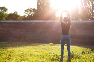 Egzersiz daha önce stadyumda germe çekici sportif modeli. Açık güneş ışınları ile vurdu. Boş alan