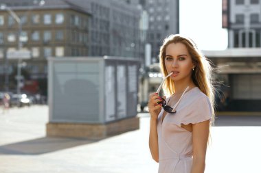 Baştan çıkarıcı sarışın model uzun saç tutan güneş gözlüğü ve kameraya bakıyor. Boş alan