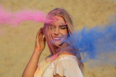 Pembe ve mavi kuru boya Holi çölde, bir bulut poz pozitif sarışın kız