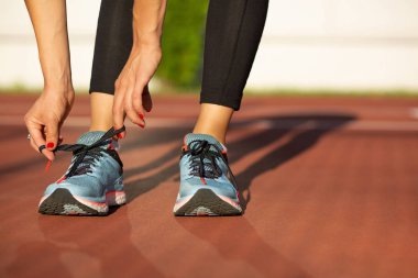 Genç fitness kadın ayakkabı bağı Stadyumu'nda güneşli akşamları bağlıyor. Metin için yer