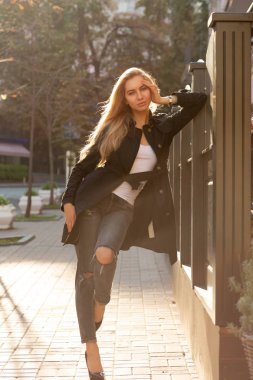 Güneşli sonbahar portre siyah palto giyiyor ve sokağın poz moda sarışın kadın
