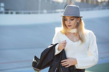 Street güneş ışığı ile poz şapka ve kazak giyen muhteşem sarışın kadın sokak portresi. Metin için yer