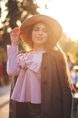 Şapka, bluz ve sonbahar parkta poz ceket giyen mutlu esmer kadın