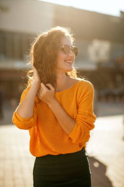 Korku veren genç modeli şık kıyafeti giymiş ve güneşli Caddesi'nde yürürken güneş gözlüğü