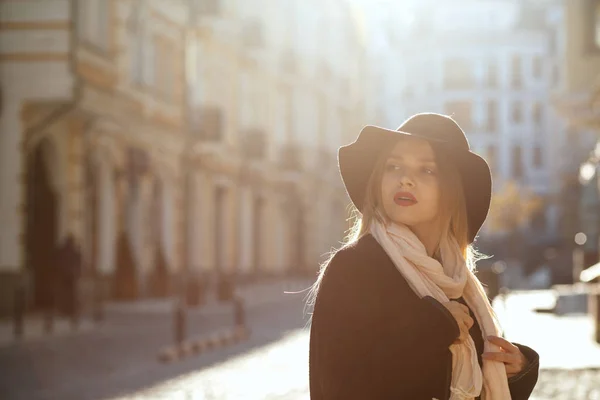 ファッショナブルな金髪女性を着て帽子 マフラー コート 太陽光線の古い通りを歩いてします テキストのためのスペース — ストック写真